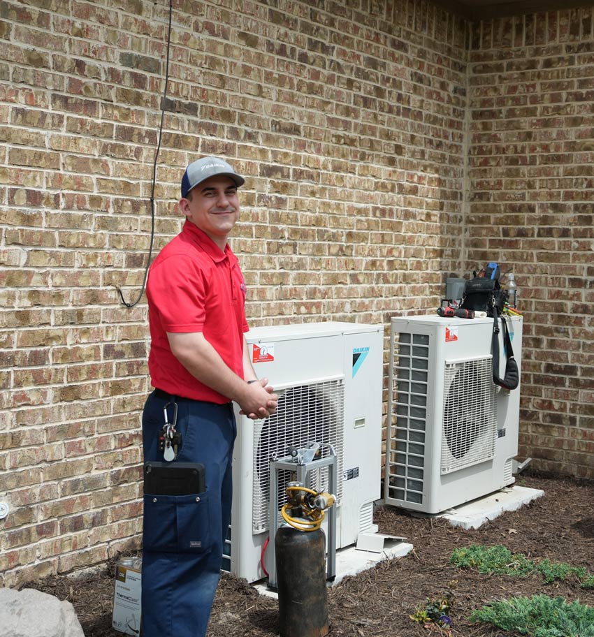 Minuteman technician standing beside a heating system during a repair service visit