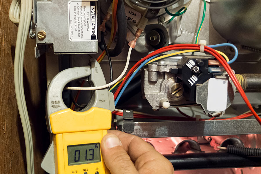 Technician testing furnace electrical components during a heating repair service in Arlington, TX