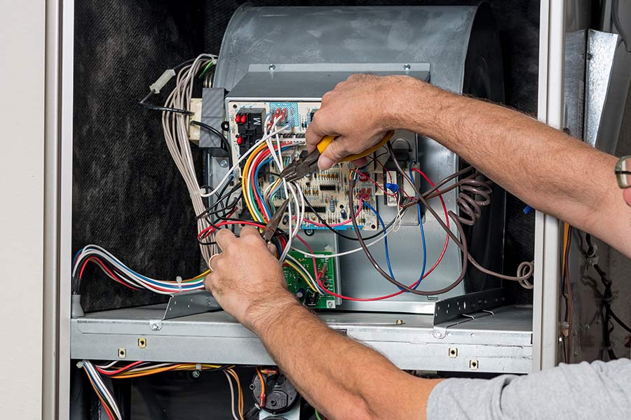 Minuteman technician inspecting furnace electrical components during maintenance in Arlington, TX